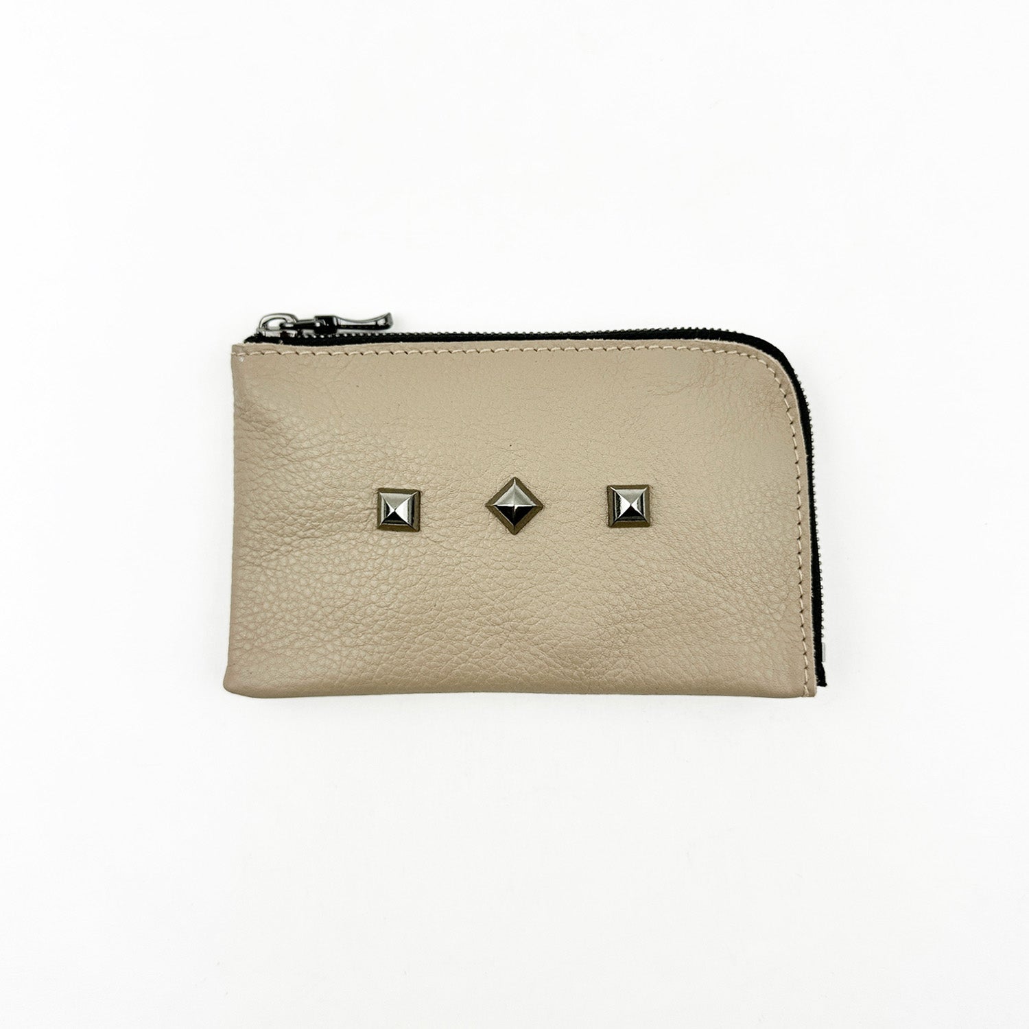 Introducing the MINI WALLET - SAND by evokewomen, a beige leather accessory with a zipper and enhanced with three square metal studs on one side for a distinctive look.