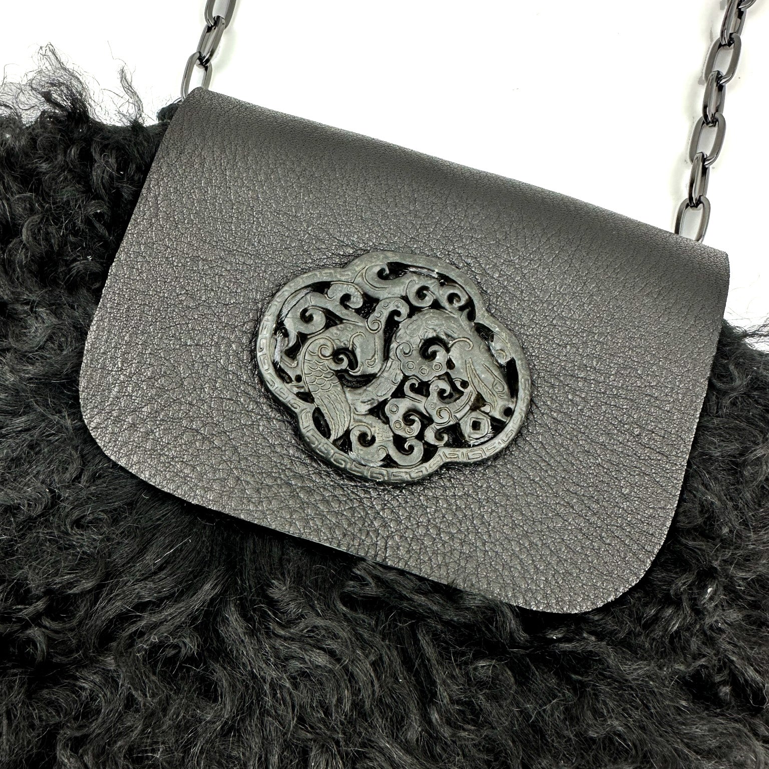 The MIA - BLACK bag by evokewomen is a breathtaking black leather creation, expertly crafted to be used as either a shoulder or crossbody bag. It features an intricate metal clasp adorned with two birds in a circular pattern, enhancing its sophisticated allure.