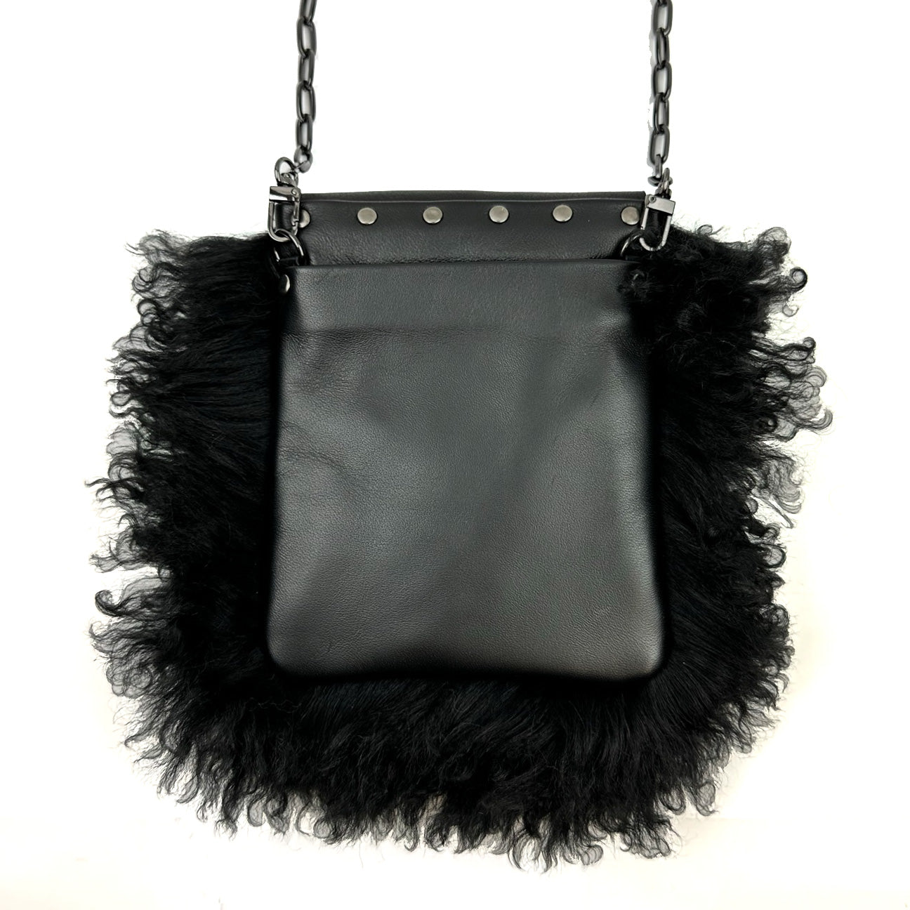 The MIA - BLACK by evokewomen features a black leather body accented with fluffy, textured edges and a chic metal chain strap, highlighted by eye-catching metal studs at the top.