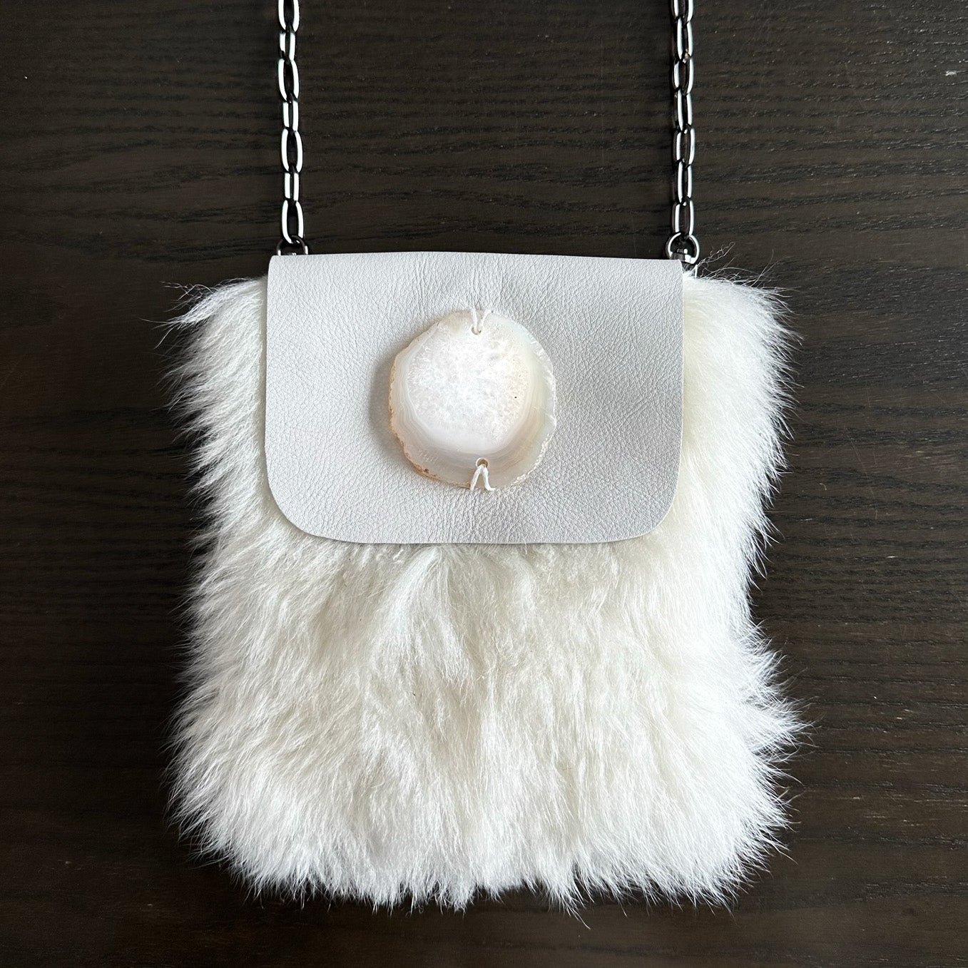 Introducing the MIA - OFF WHITE by evokewomen, a chic small handbag crafted from white faux fur, featuring a silver chain strap and a stunning agate stone accent on the flap. Ideal as a crossbody bag for effortlessly adding elegance to any outfit.