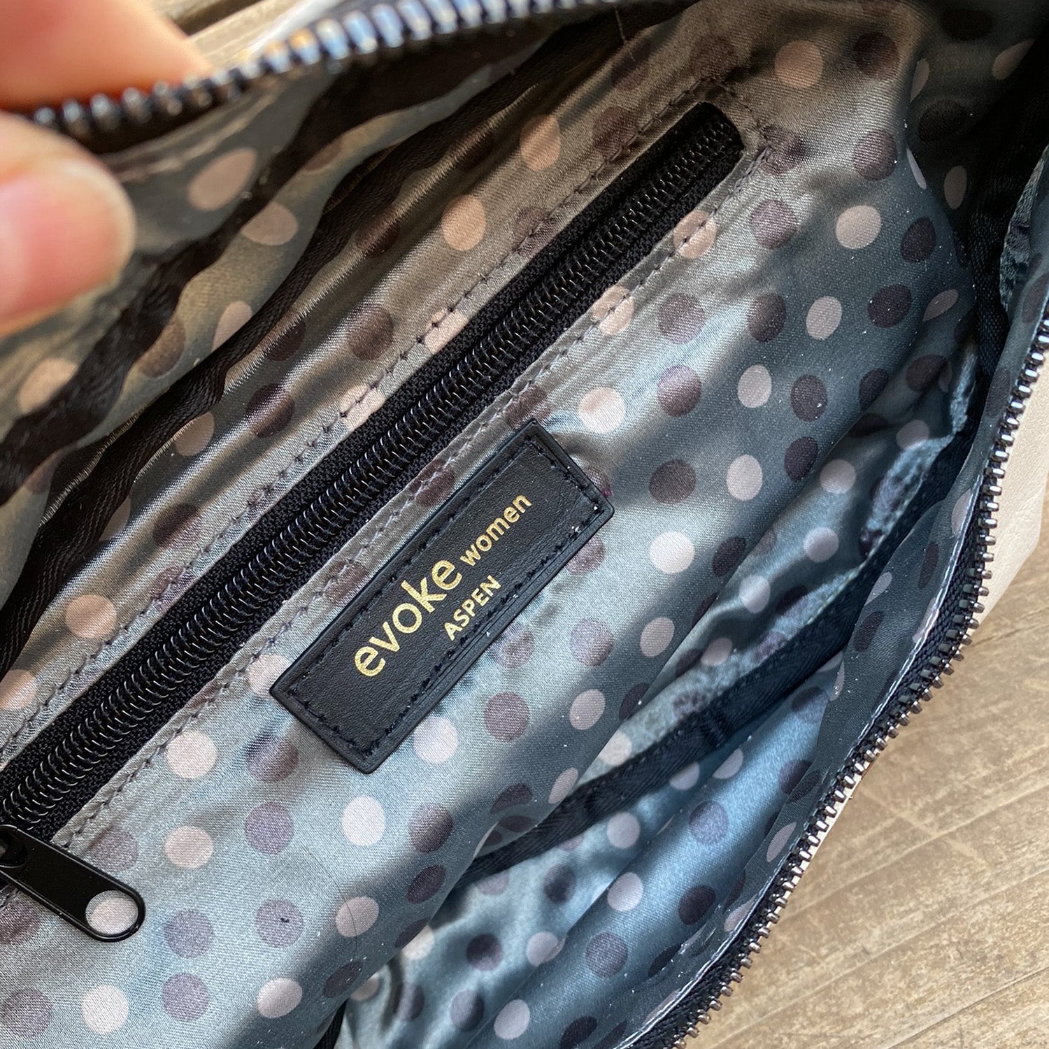 Open polka dot cross body bag featuring a zippered pocket and a label that reads "evokewomen STELLA - PUTTY.