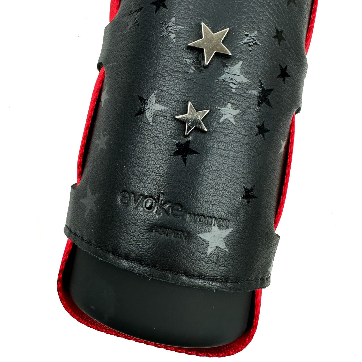 Close-up of the "Carrier - black stars," a leather accessory by evokewomen featuring metal star embellishments and embossed branding in the center, bordered by red trim. This stylish piece can also serve as a chic bottle carrier, complete with an adjustable shoulder strap for convenience.