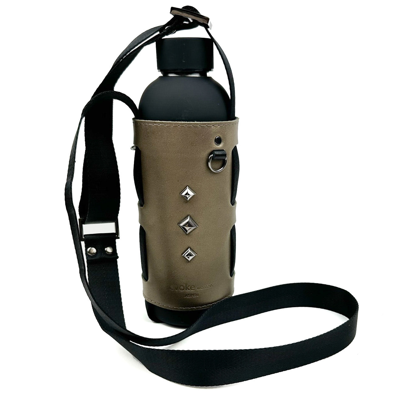 The Bottle Carrier - bronze by evokewomen features a water bottle encased in a brown leather holder with a corset-style closure embellished with decorative studs and pyramid-shaped rivets, complemented by a black adjustable strap.