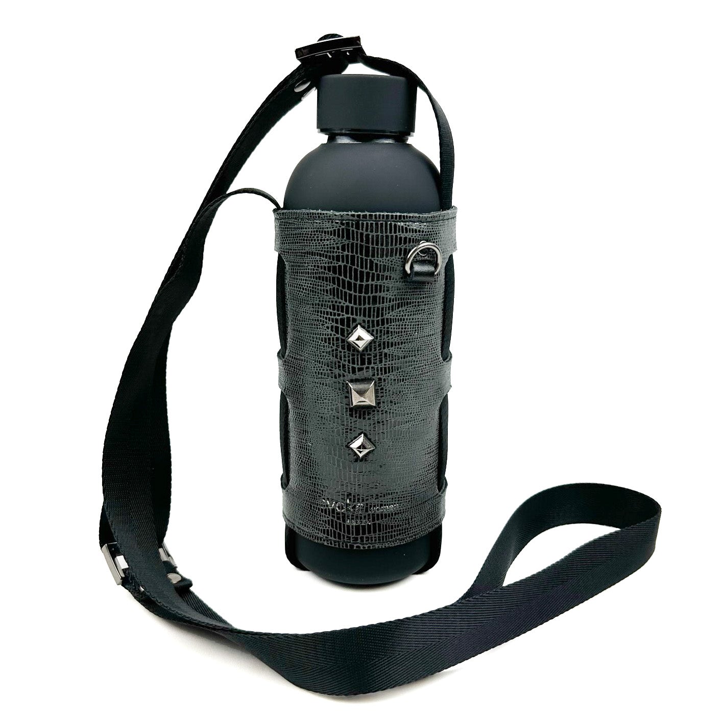 The Bottle Carrier - snake from evokewomen is a black water bottle accessorized with a textured, studded cover and an adjustable shoulder strap, elegantly designed to resemble faux snake leather.