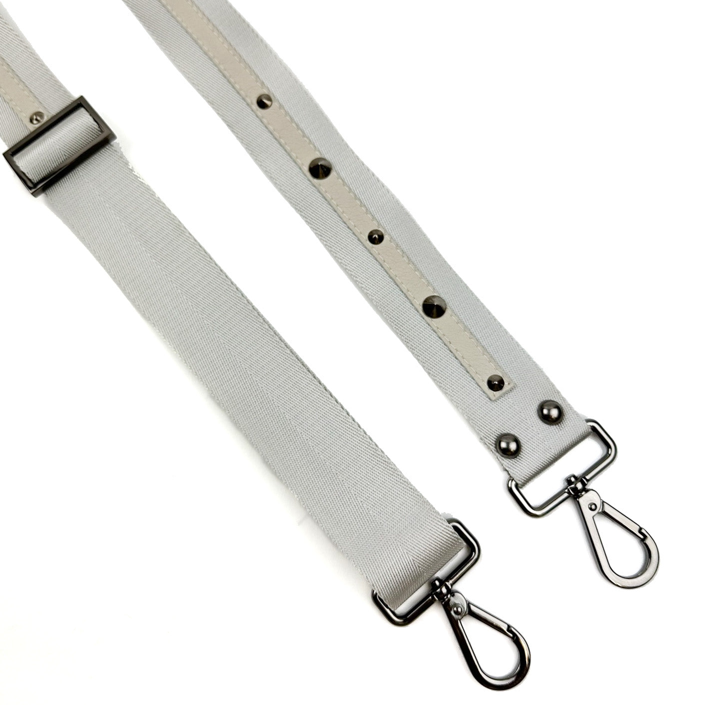 The SHOULDER STRAP - LIGHT GREY by evokewomen features two light gray nylon webbing straps adorned with leather accents, metal clips, and grommets, all showcased against a white background.