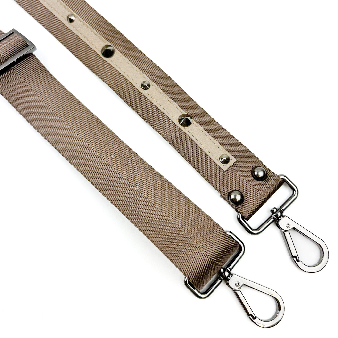 Product Description: The SHOULDER STRAP - SAND by evokewomen features two beige adjustable nylon webbing straps adorned with metal clips and rivets. These straps, known for their unique design, are displayed on a white background.
