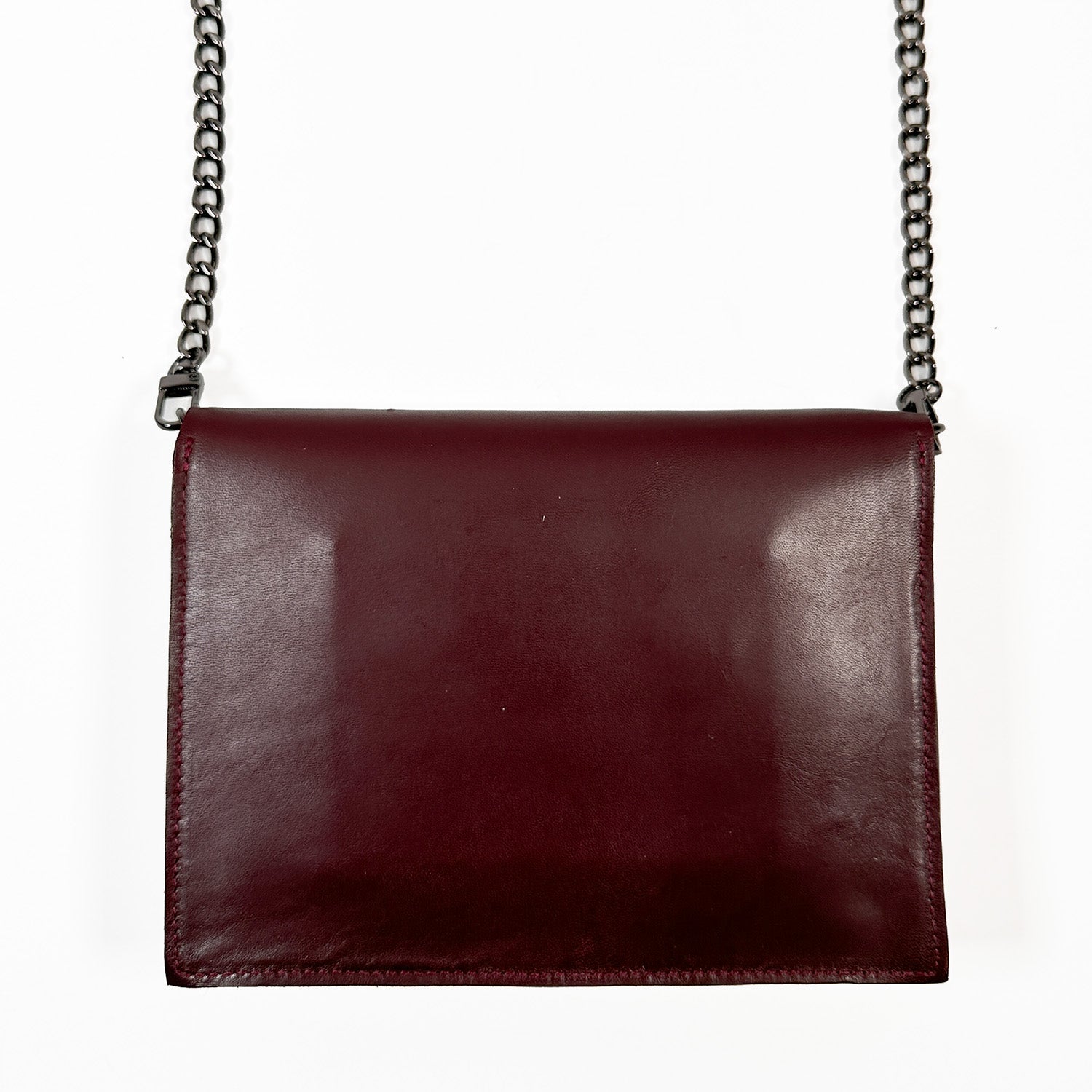 This sophisticated BAHAMA crossbody bag by evokewomen, crafted from Italian leather in a deep burgundy shade, boasts a striking metal chain strap that stands out beautifully against a white background.