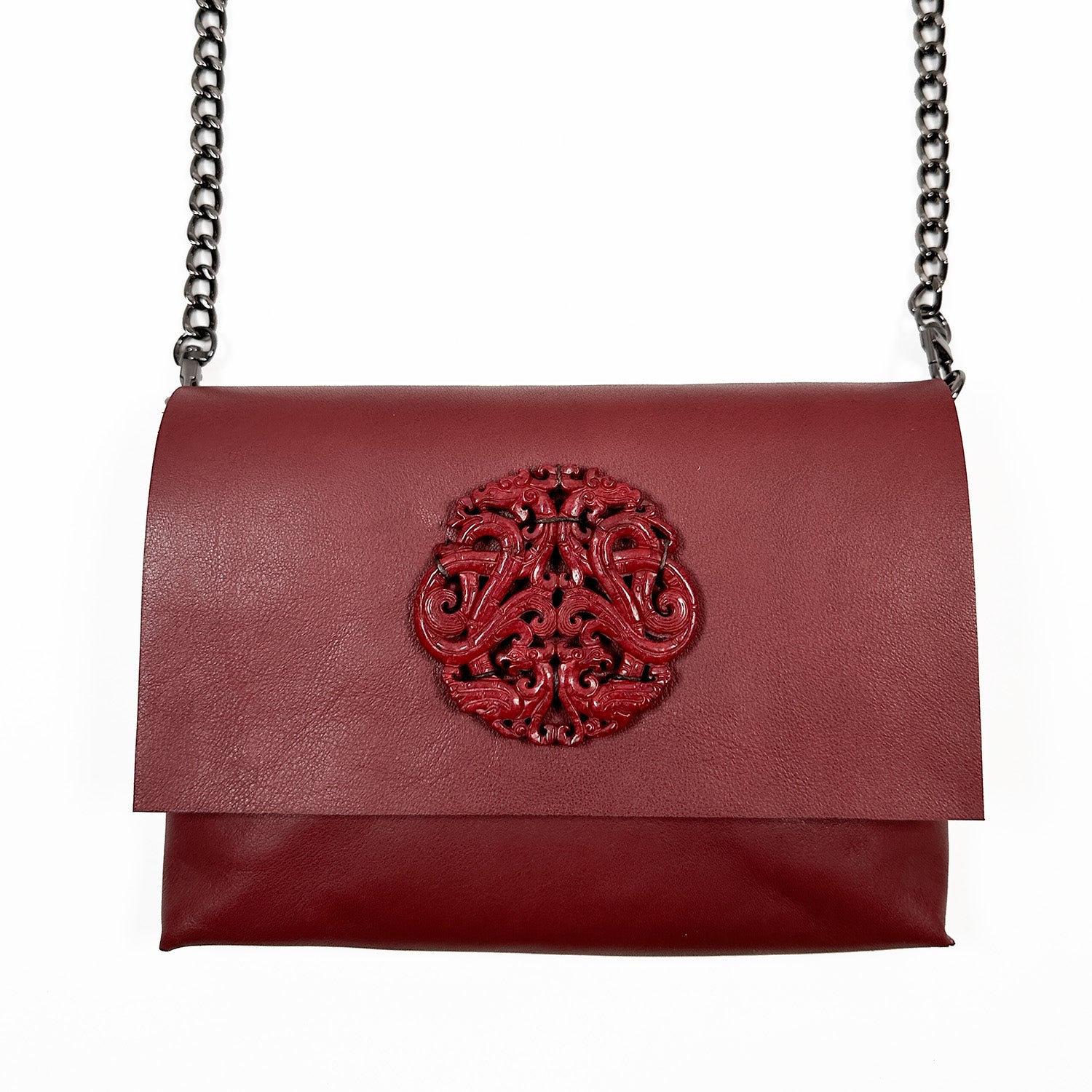 The BAHAMA purse by evokewomen, crafted from Italian leather in a wine color with a chain strap and an ornate embossed circle design on the front, offers both elegance and versatility.