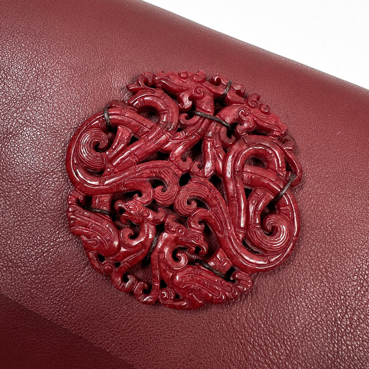 The BAHAMA - wine by evokewomen showcases a breathtaking red ornate dragon design embossed on textured maroon Italian leather, making it a versatile bag for all occasions.