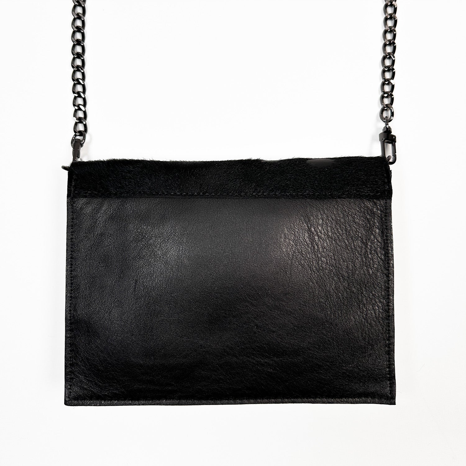 The BAHAMA –BLACK FUR FLAP by evokewomen is an Italian leather handbag featuring a gunmetal chain strap, elegantly displayed against a white background.