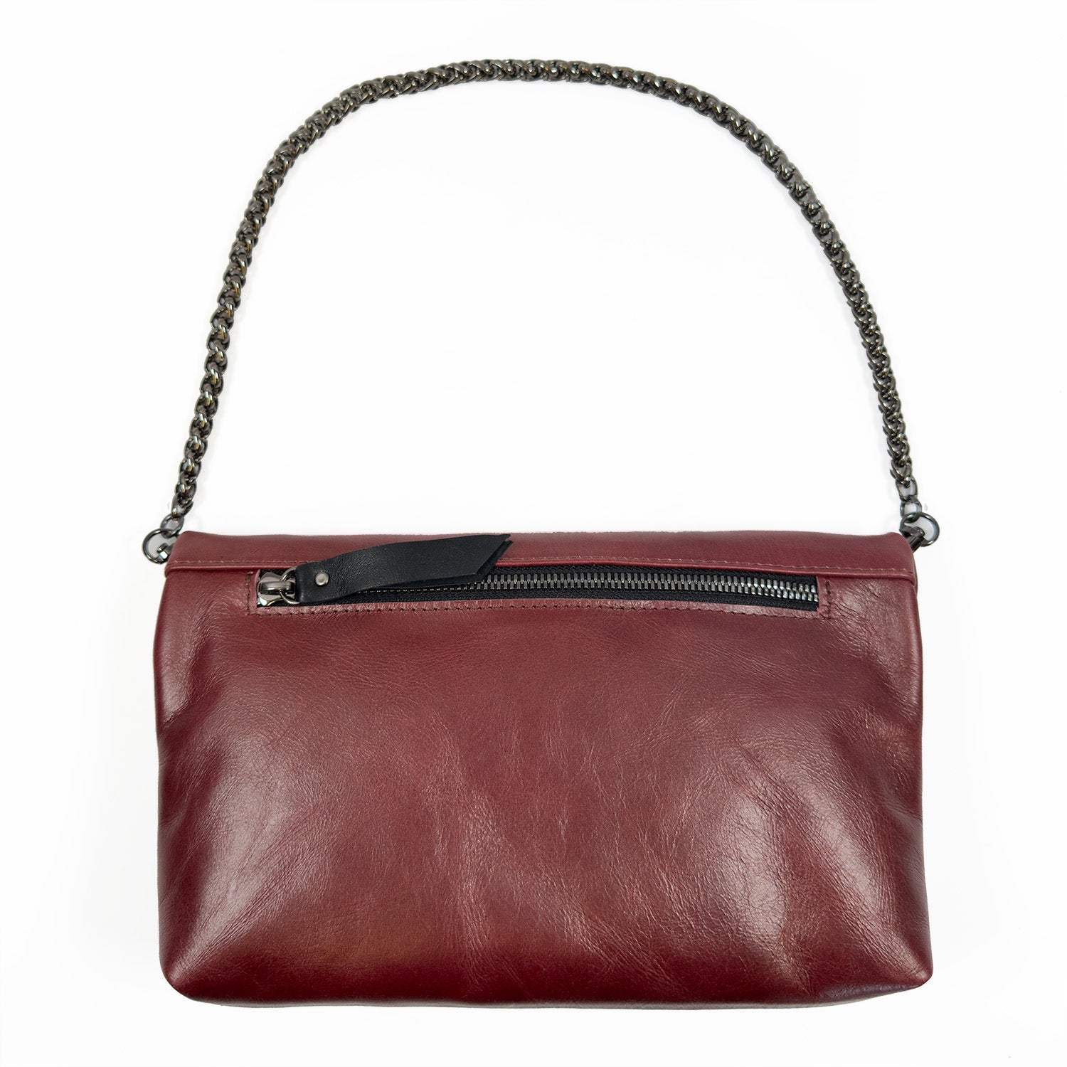 The Farah - wine clutch by evokewomen is a maroon leather fold-over piece featuring a sleek snake spine chain. It is complemented by a black zipper adorned with a Tigereye Buddha charm, all beautifully set against a white background.