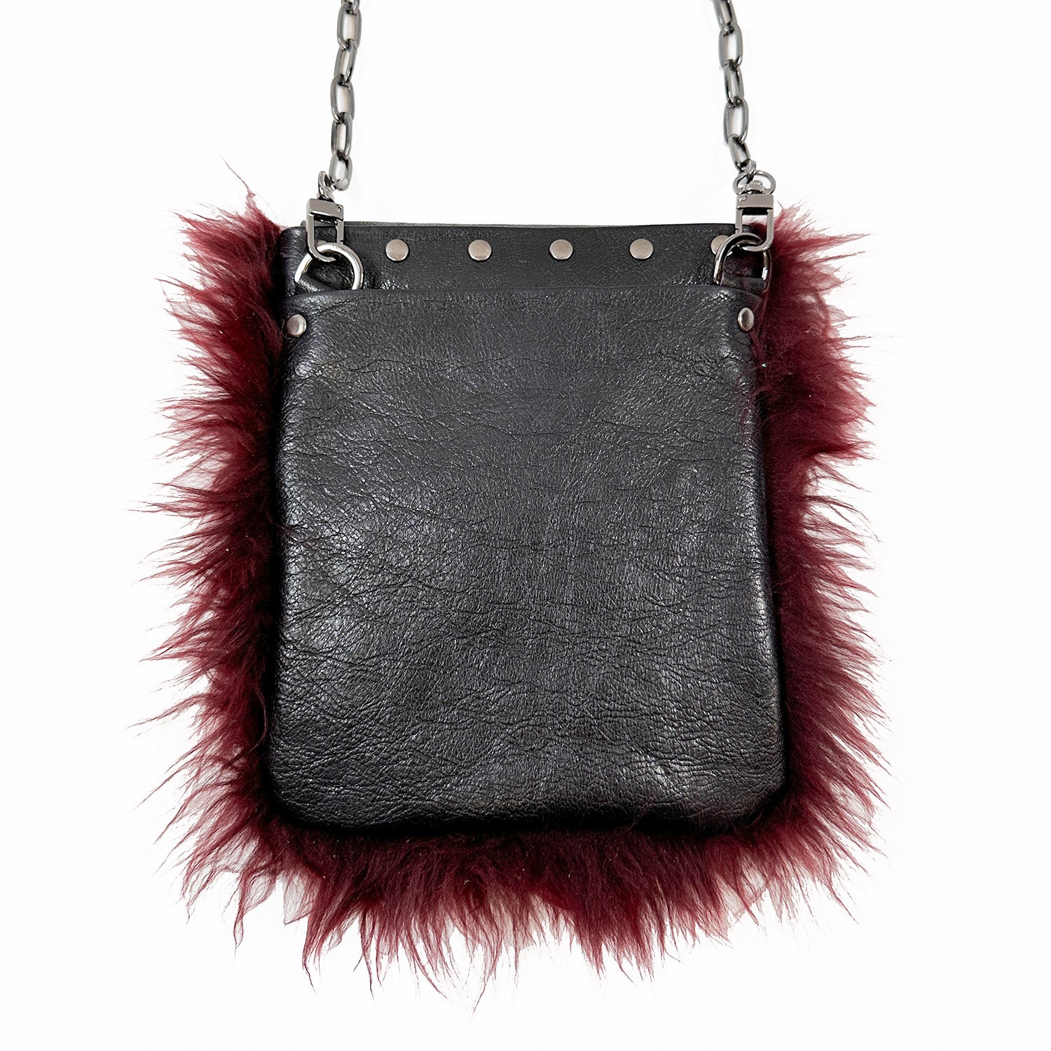 A MIA - BURGUNDY cross body handbag by evokewomen, featuring black leather with burgundy fur trim and a silver chain strap, against a white background.