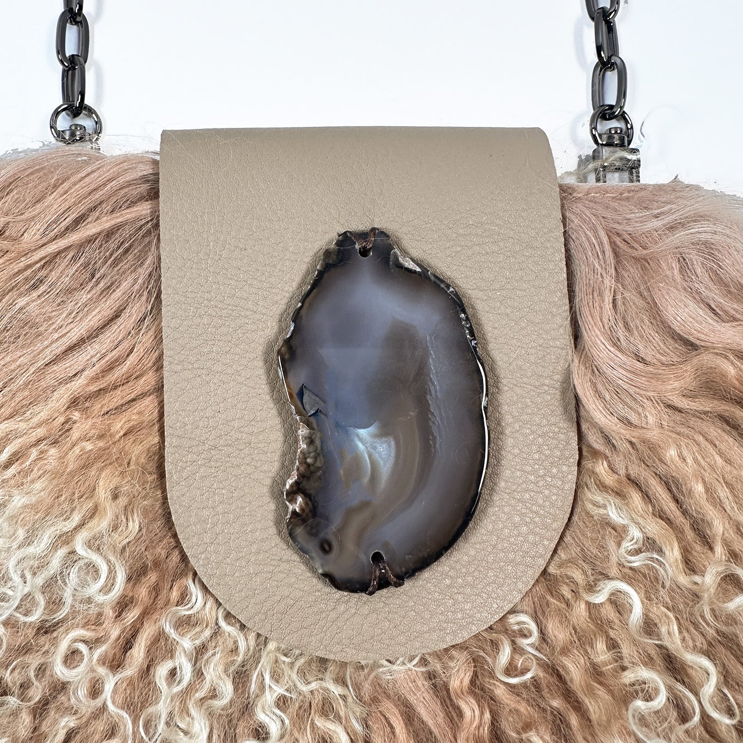 The MIA - BEIGE by evokewomen is a beige leather crossbody bag featuring luxurious Mongolian lamb fur trim and a fashionable chain shoulder strap, ideal for creating a chic statement.