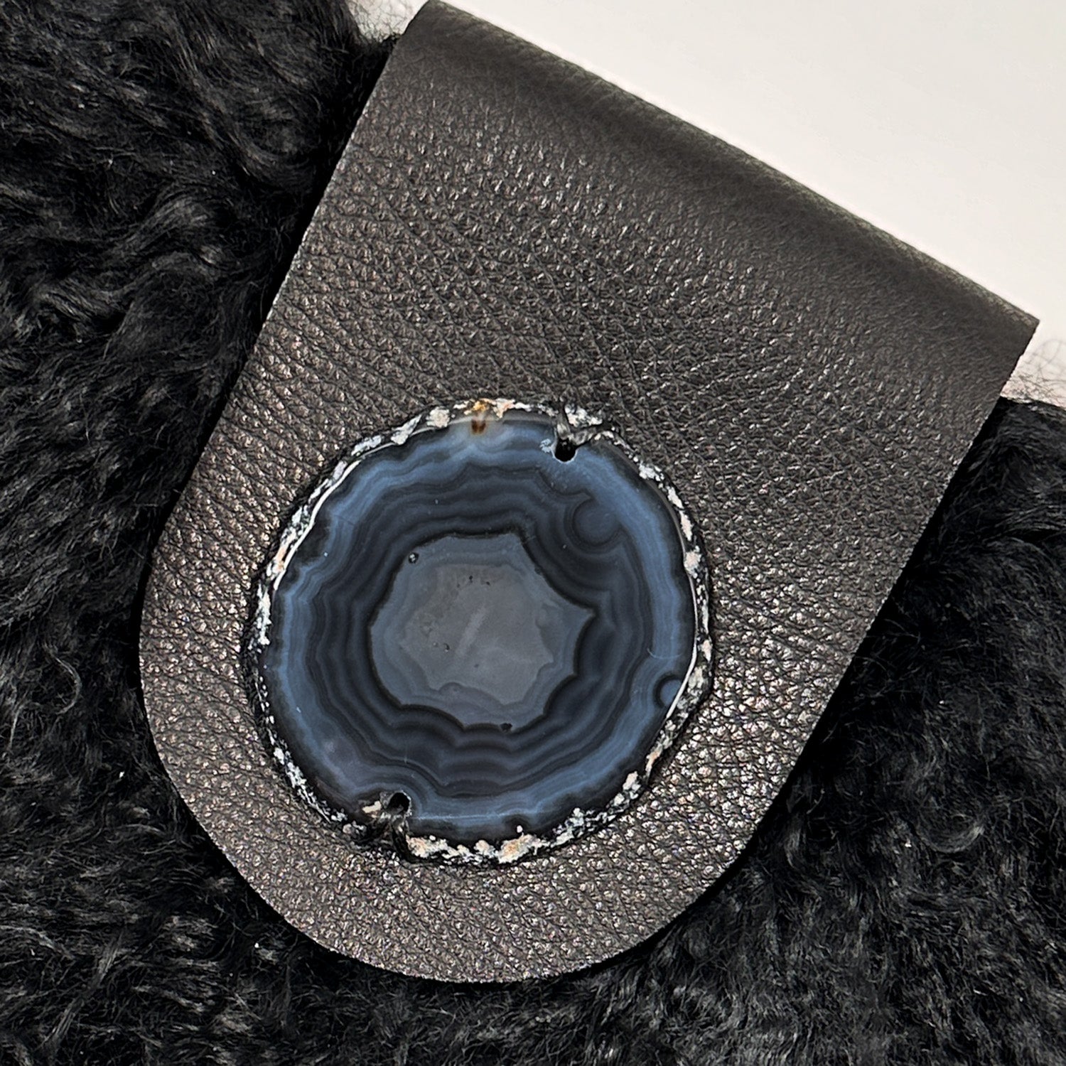 The MIA - BLACK by evokewomen is a black leather crossbody bag featuring a metal chain strap and fluffy black Mongolian lamb fur trim.