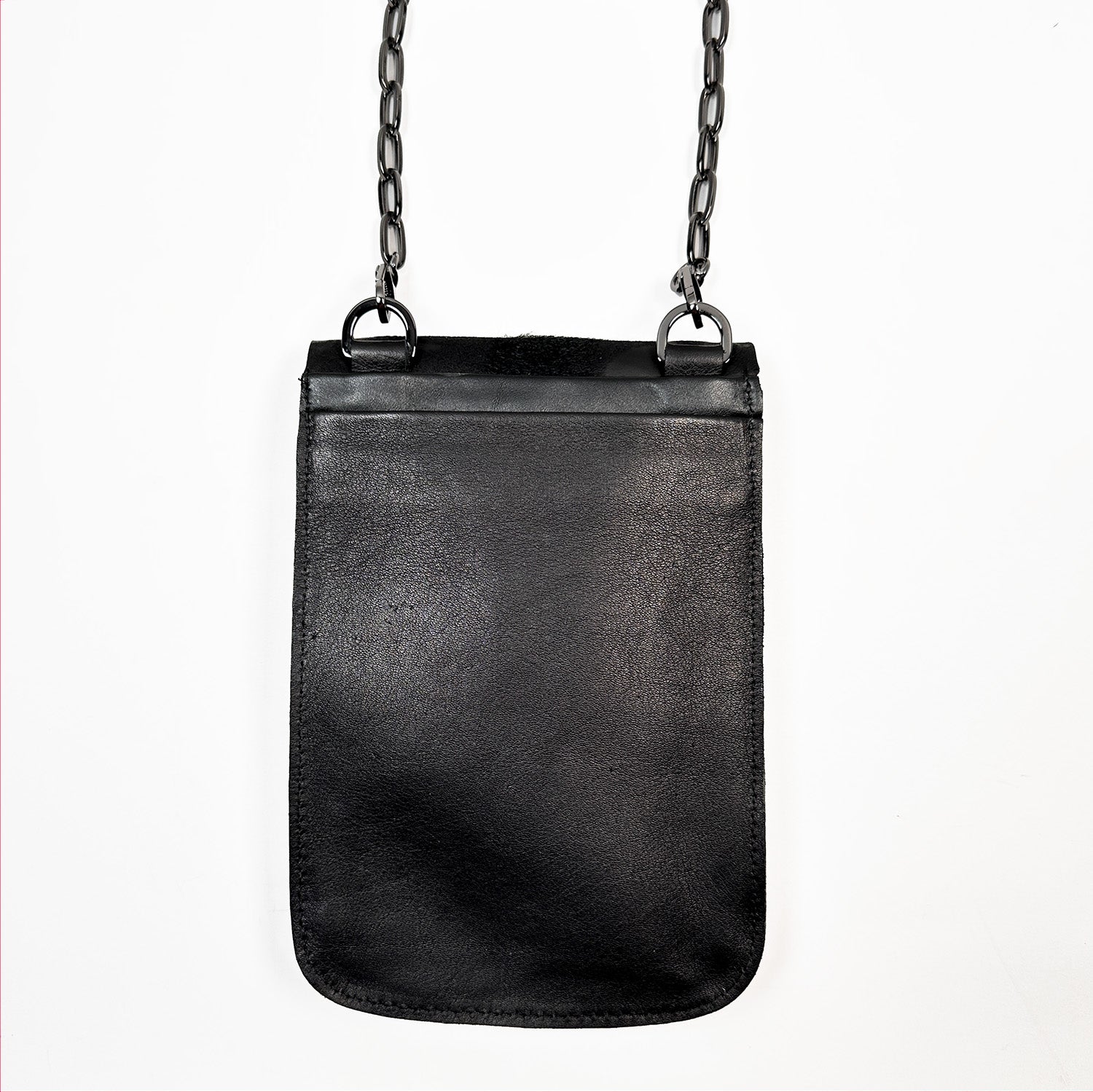 The PAULINA - BLACK FUR FLAP by evokewomen is a small rectangular crossbody bag made from sumptuous Italian leather, adorned with a chic gunmetal chain strap hanging elegantly against a pristine white background—a true festival essential.