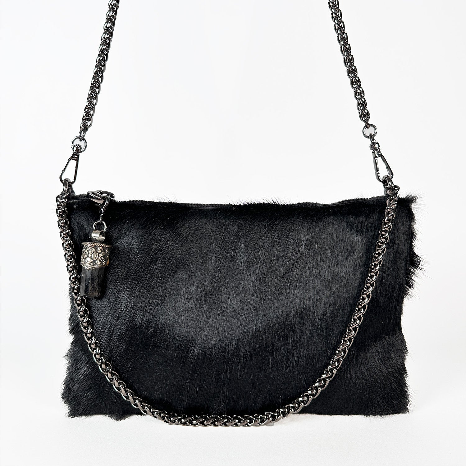 Introducing the POPPY - BLACK by evokewomen, a luxurious shoulder bag in black with a goat fur texture, featuring a metal chain strap and adorned with a small decorative charm on the handle.