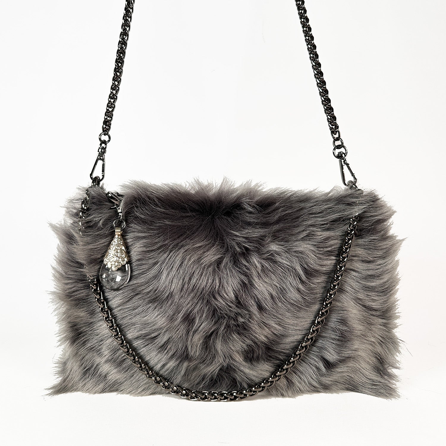 The POPPY - GREY LIGHT TIPPED handbag from evokewomen features Toscana lamb fur in gray, a black chain strap, and is adorned with a decorative Tibetan crystal rock pendant.