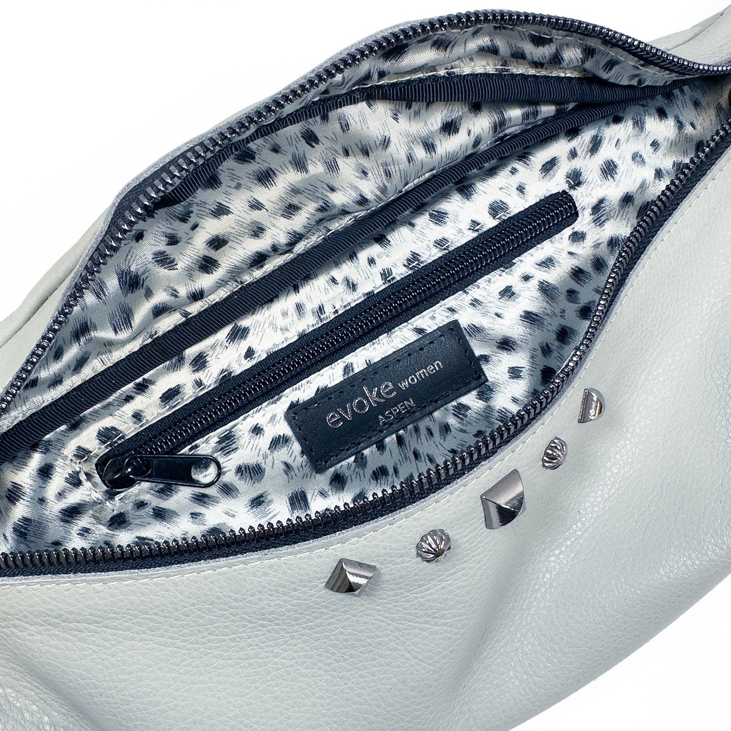 STELLA - light smoke sling bag in white leather features a leopard print interior, a zippered pocket, and metallic rivet accents, branded with "evokewomen.