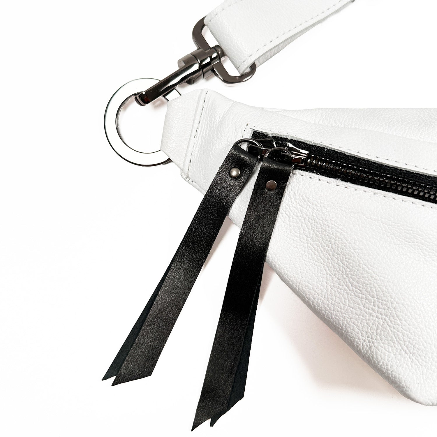 Close-up of the evokewomen STELLA - white - skull sling bag crafted from Italian leather, featuring a metal ring, zipper, black leather pull tabs, and a detachable tassel.