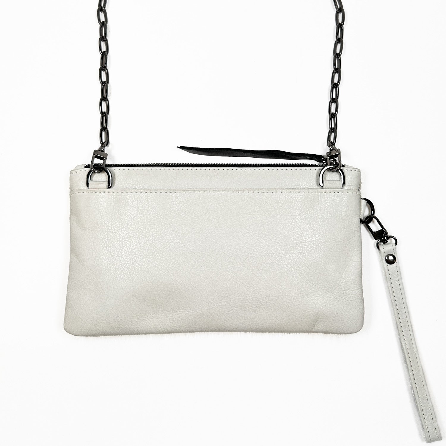 The VICTORIA by evokewomen is an off-white leather crossbody bag with a black chain strap and zipper, featuring a detachable wristlet for added convenience.