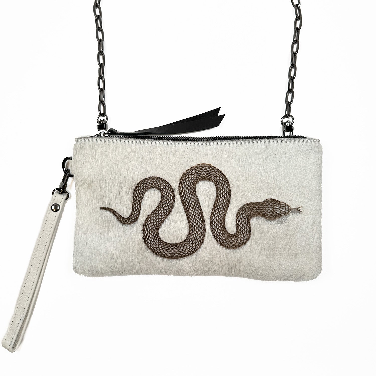 Introducing the VICTORIA clutch by evokewomen, an off-white accessory with a striking laser snake design on the front. It features a chain strap for versatile cross-body styling and a secure zip closure.