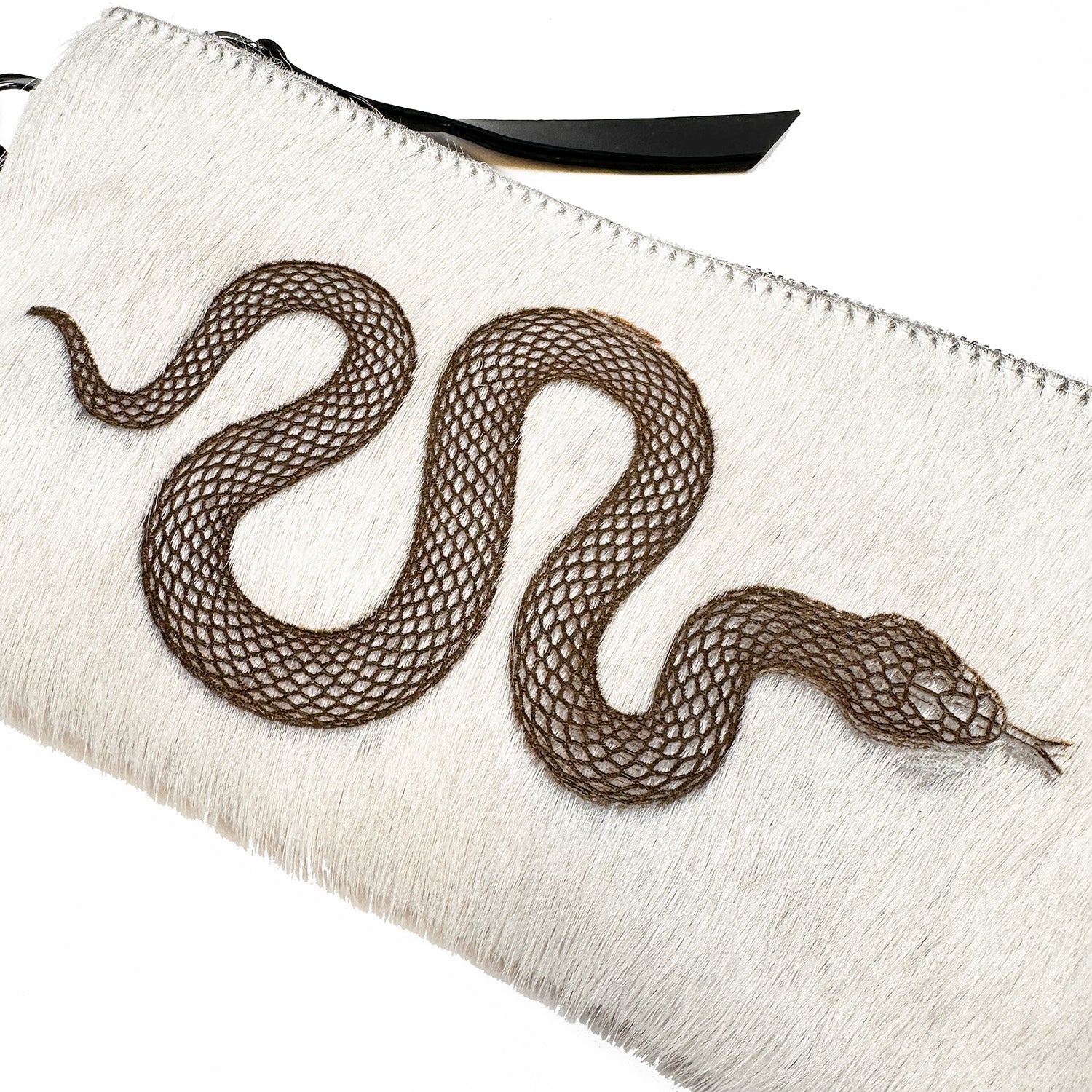 An off-white VICTORIA clutch purse with a brown laser snake design on the front, crafted by evokewomen, is perfectly versatile as a wristlet for any occasion.