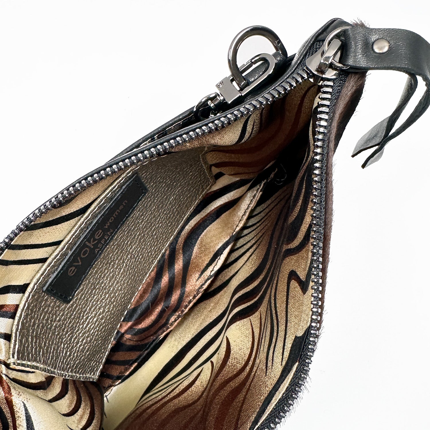 The VICTORIA crossbody bag from evokewomen features an open black leather exterior with a laser snake design, a patterned interior, and a metallic zipper.