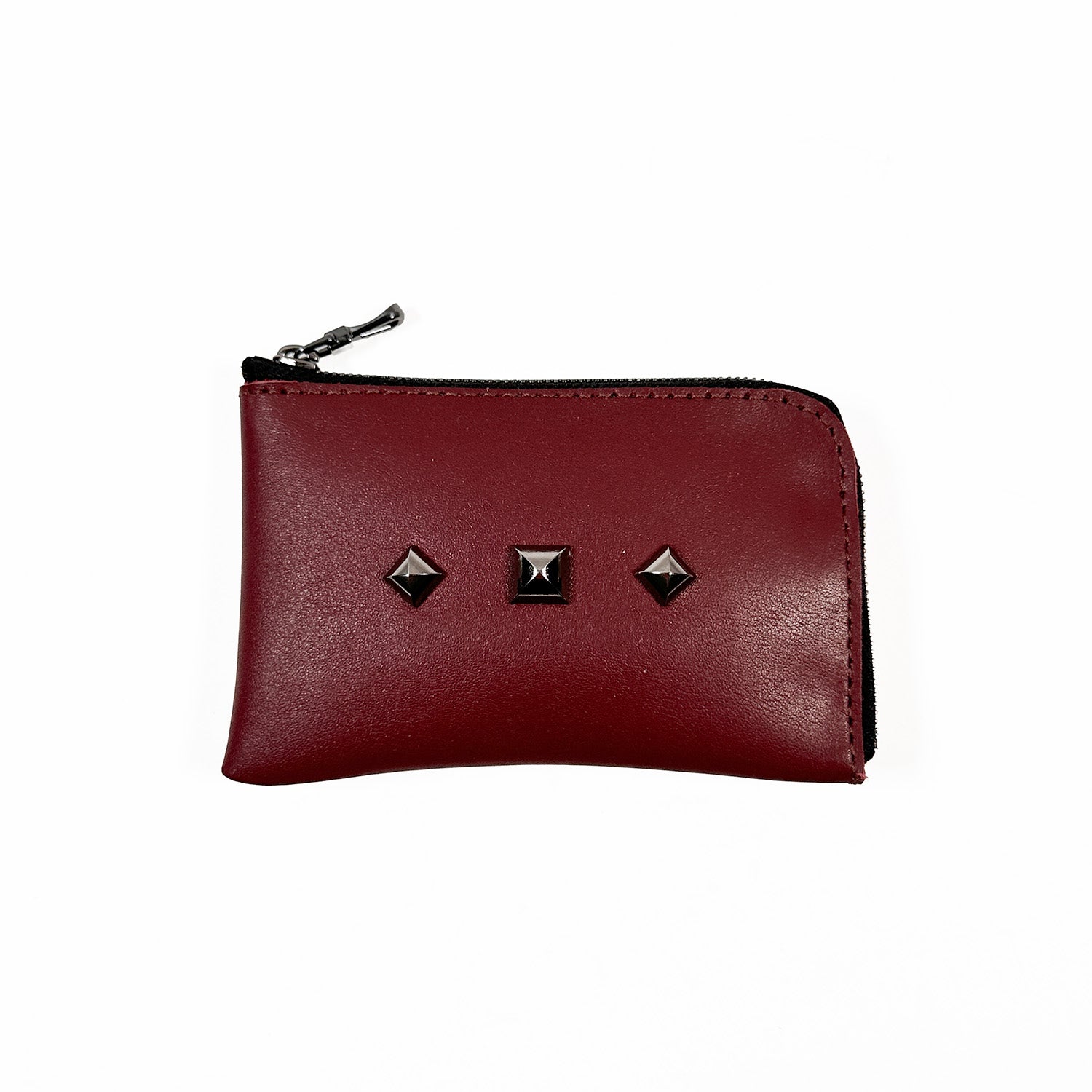 The evokewomen MINI WALLET - wine is a compact maroon leather accessory featuring a zipper and three square black studs on one side, highlighting its unique design.